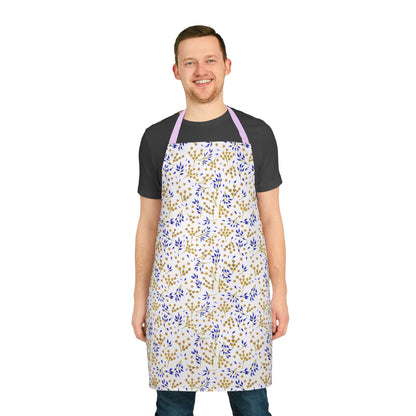 Smiling man models the Floral Apron from FireBrook Designs, featuring a vibrant blue and mustard leafy pattern on cream, perfect for stylish and joyful cooking or crafting.