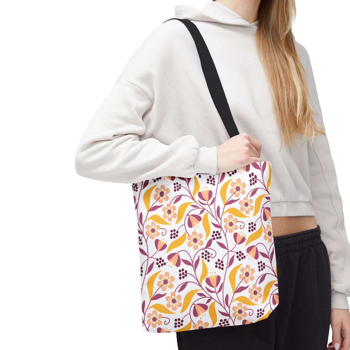 Floral Tote Bag with black straps, showcasing a vibrant mustard, dusty pink, and burgundy floral-vine pattern on white, worn by a person in a light hoodie, embodying FireBrook Essentials' joyful style.
