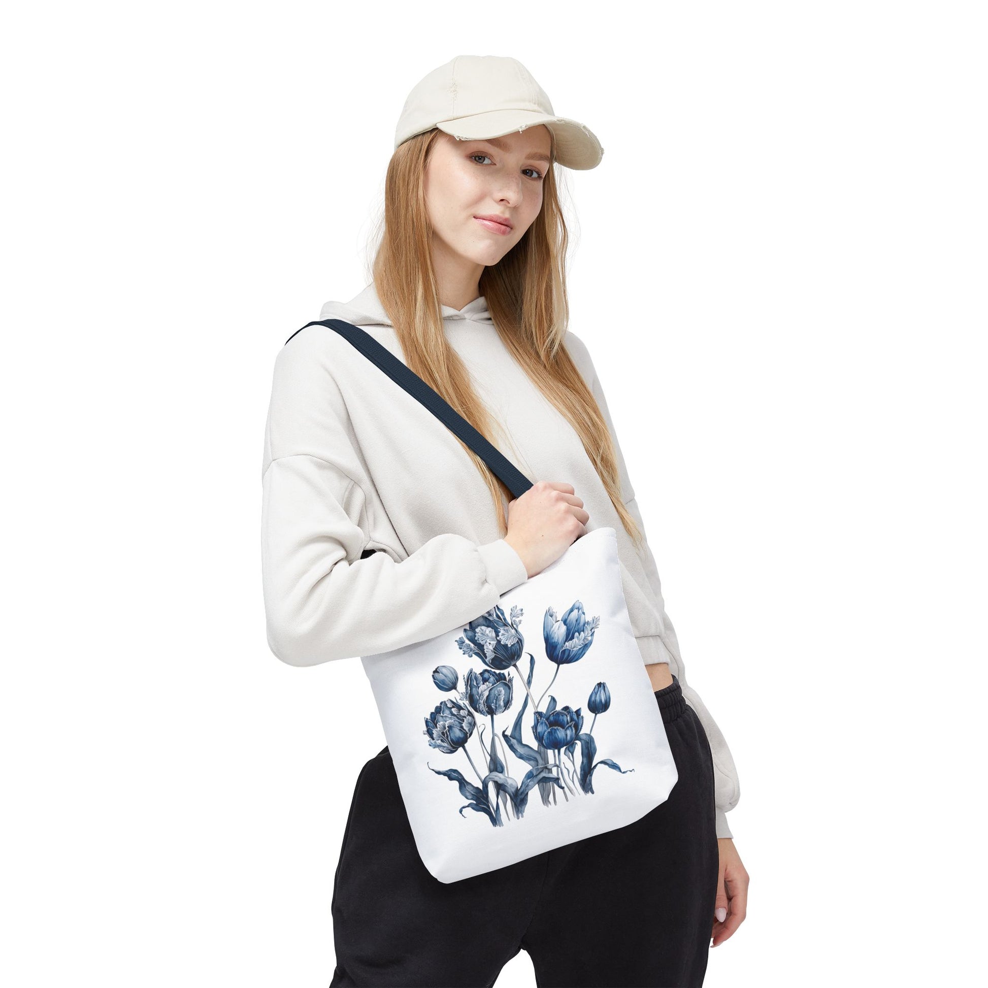 Woman wearing a hat holds a Flowers in Blue Hue watercolor tote bag, showcasing its floral design and functionality.