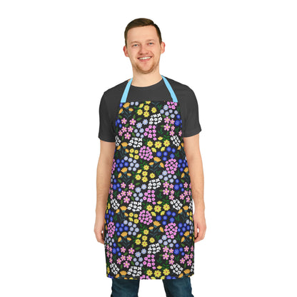Smiling young man wearing the Apron Floral Design, featuring vibrant floral patterns on a black background with a contrasting light blue neck strap, ideal for stylish and comfortable cooking or crafting.