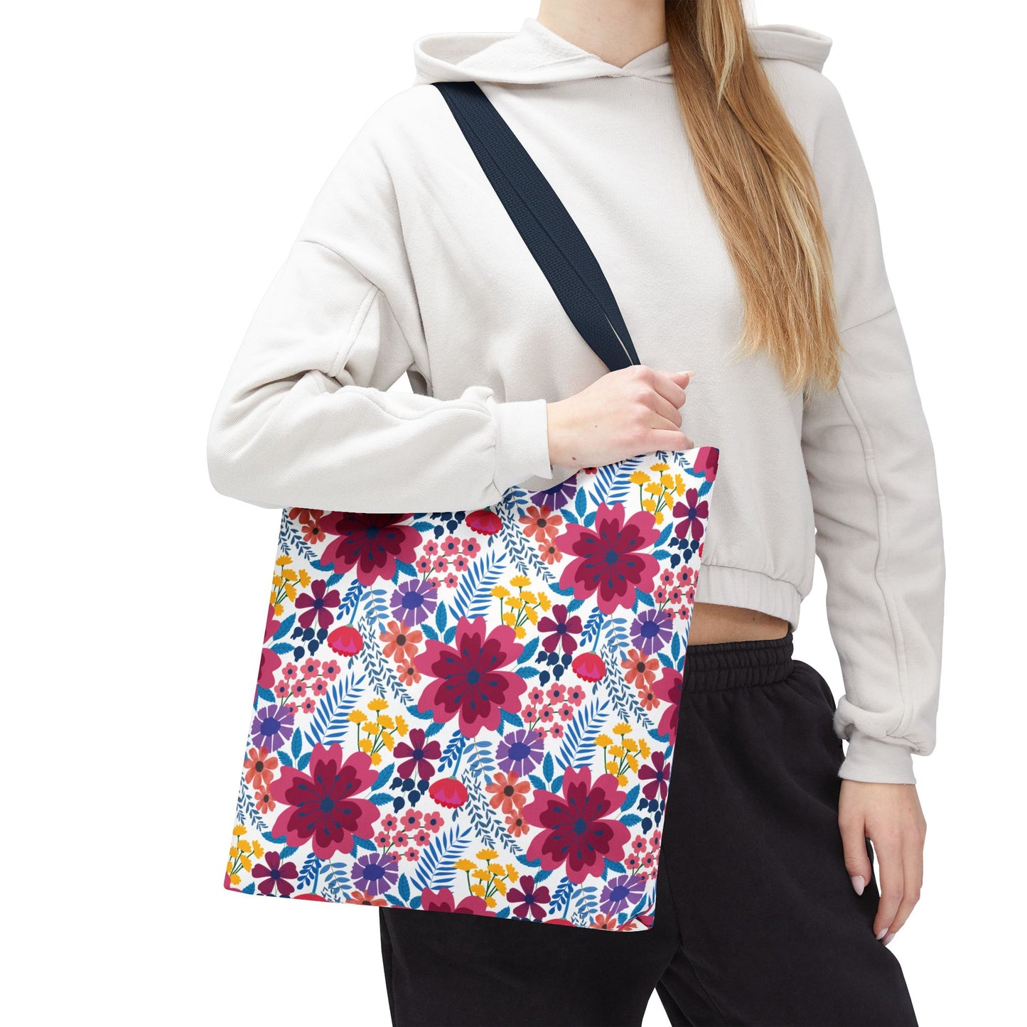 Violet Daisy Carnival Tote Bag with vibrant floral print, featuring red-pink blossoms and colorful flowers, carried by a casually dressed person. Ideal for joyful summer outings and practical use.