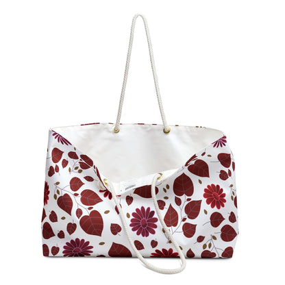 Weekender Bag with white rope handles and a T-bottom design, featuring a vibrant red and burgundy leaf and daisy pattern. Ideal for stylish travel, embodying FireBrook Designs' joyful and uplifting spirit.
