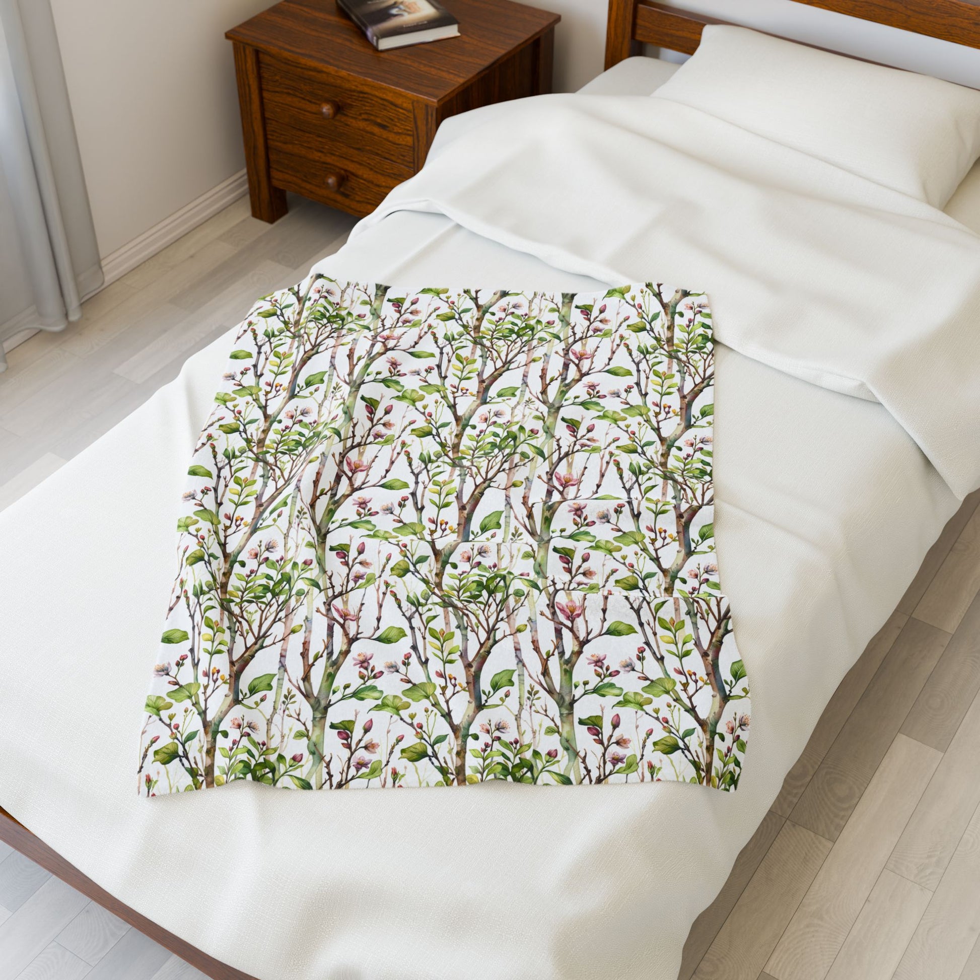 Plush Blanket - Blooming Forest Floor Design on a bed, showcasing a serene pattern of budding trees and flowers, perfect for cozying up and adding a nature-inspired touch to any room.