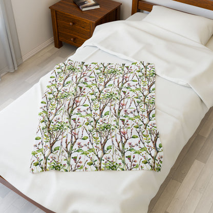 Plush Blanket - Blooming Forest Floor Design on a bed, showcasing a serene pattern of budding trees and flowers, perfect for cozying up and adding a nature-inspired touch to any room.