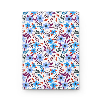 HARDCOVER JOURNAL, MATTE, RULED, 5X7, SEWN BIND, CLEAN-TEAR PAGES – BLOOM BRIGHTLY features a seamless floral pattern with blue flowers, purple and burgundy leaves, and berry-like clusters on a white background.