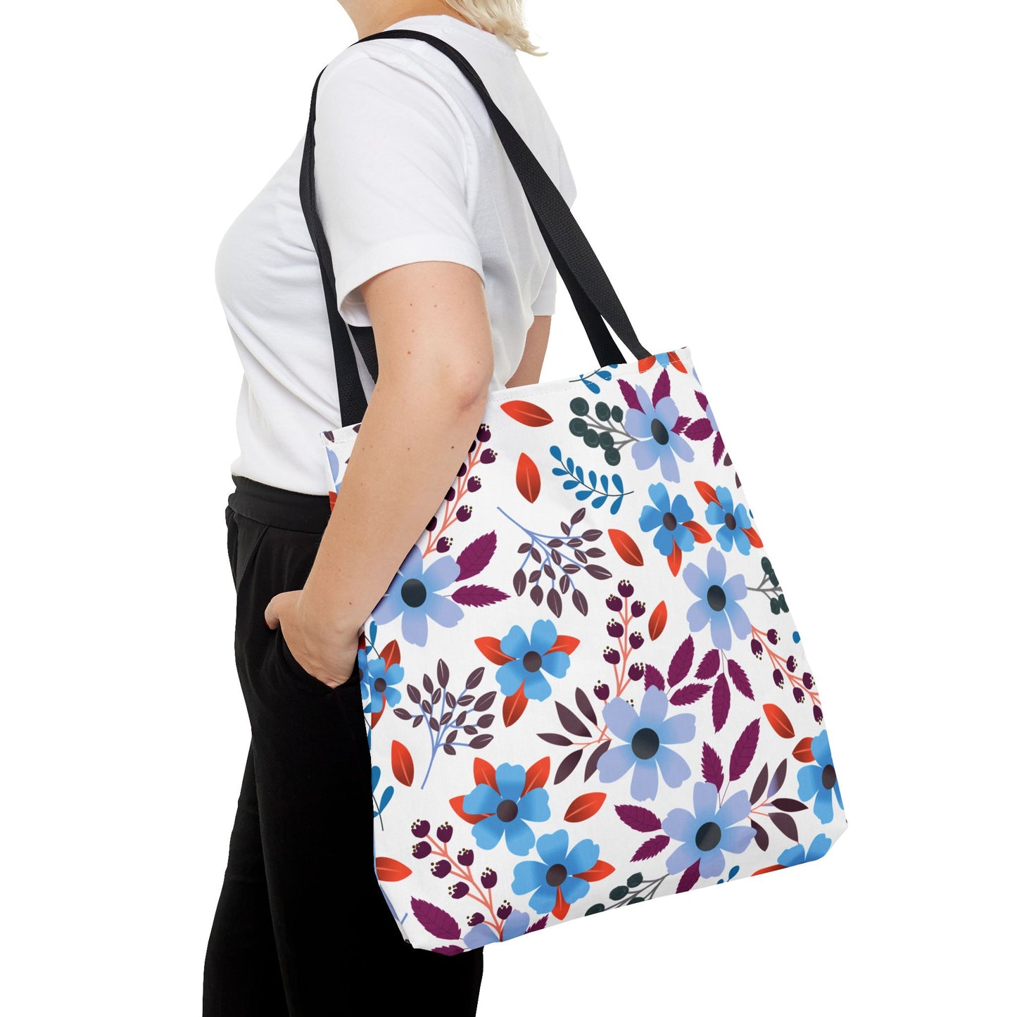 Floral Tote Bag: A person carries a stylish, white tote adorned with vibrant blue and purple flowers, ideal for summer outings. Features durable polyester, reinforced handles, and ample space for essentials.