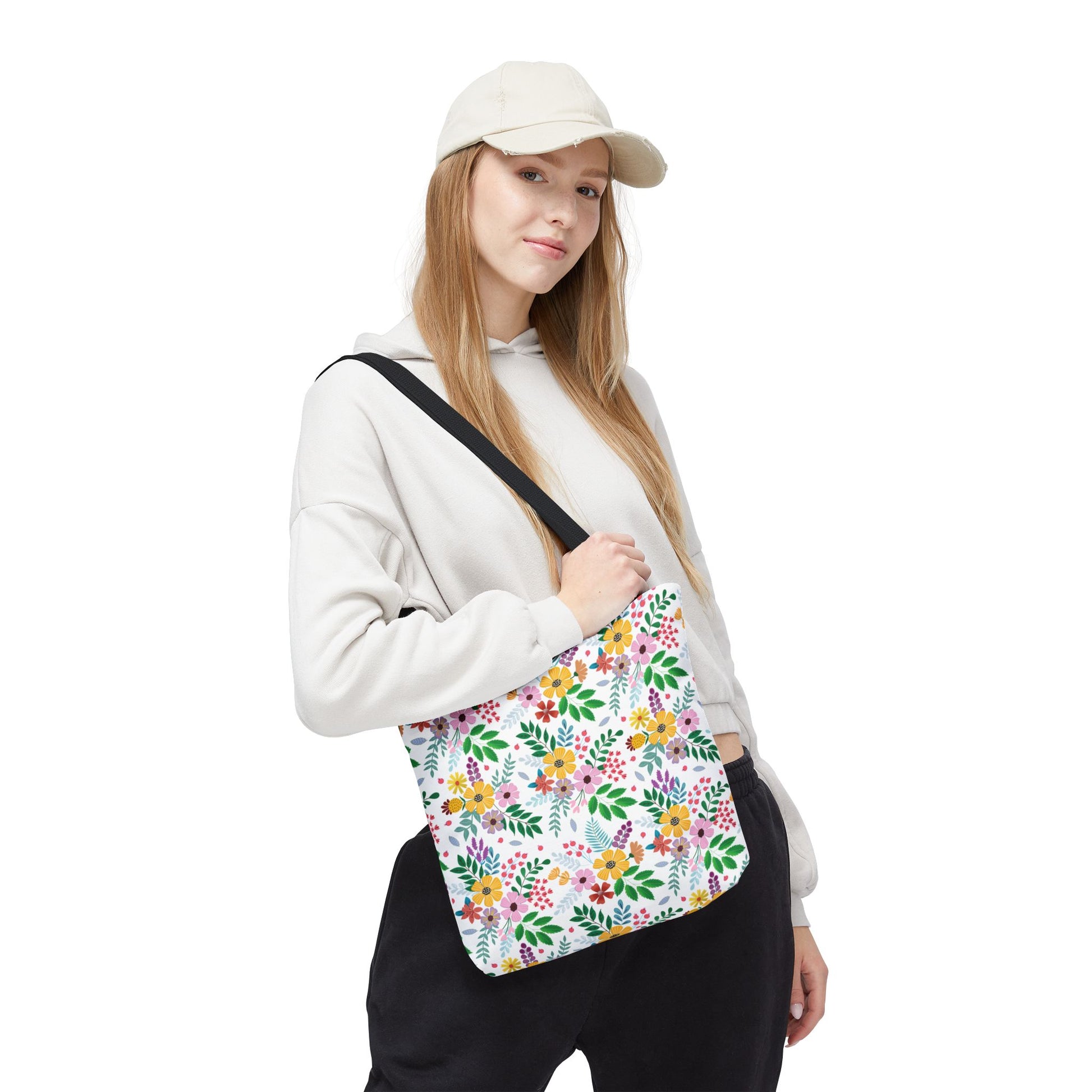 A young woman models the Spring Floral Patch Tote Bag, showcasing its vibrant, multicolored floral pattern. Ideal for summer outings, this durable, stylish bag embodies FireBrook Designs' ethos of uplifting, joyful apparel and accessories.
