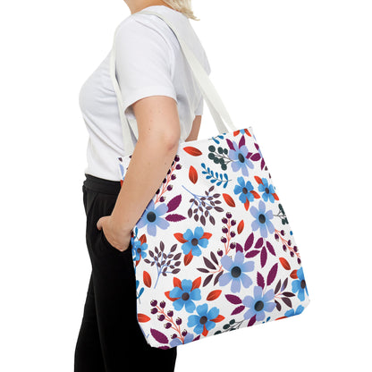 Floral Tote Bag carried over the shoulder, featuring a vibrant pattern with blue, lavender flowers, deep purple leaves, and red accents. A stylish, durable accessory from FireBrook Essentials for joyful outings.