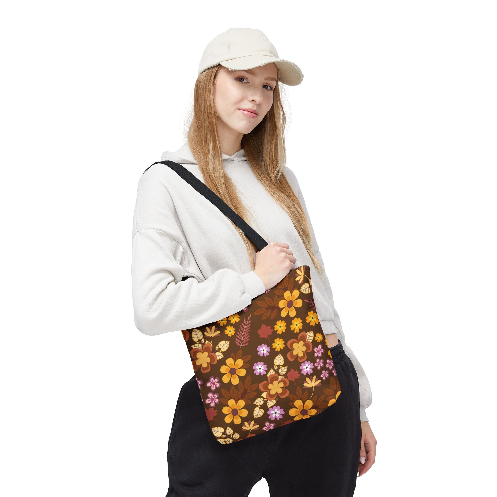 A young woman wears a light hoodie and cap, carrying the Floral Tote Bag with vibrant yellow, orange, and purple floral patterns, ideal for joyful summer outings.