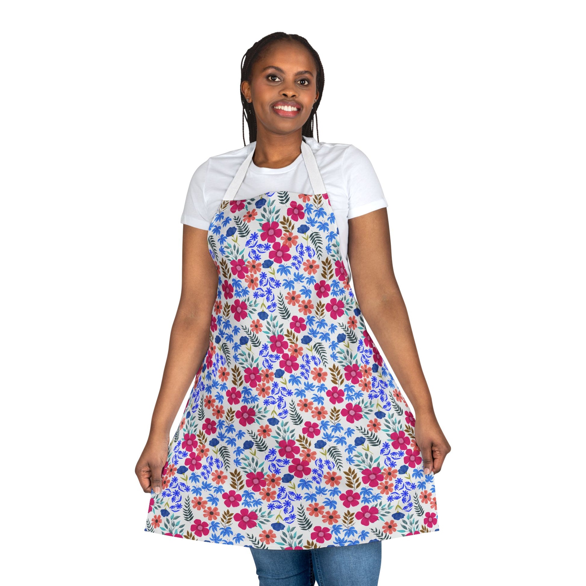 Smiling woman wearing the Apron Floral Design over a white t-shirt and jeans, showcasing its vibrant multicolored floral pattern, embodying FireBrook Essentials' blend of style and functionality for joyful everyday use.