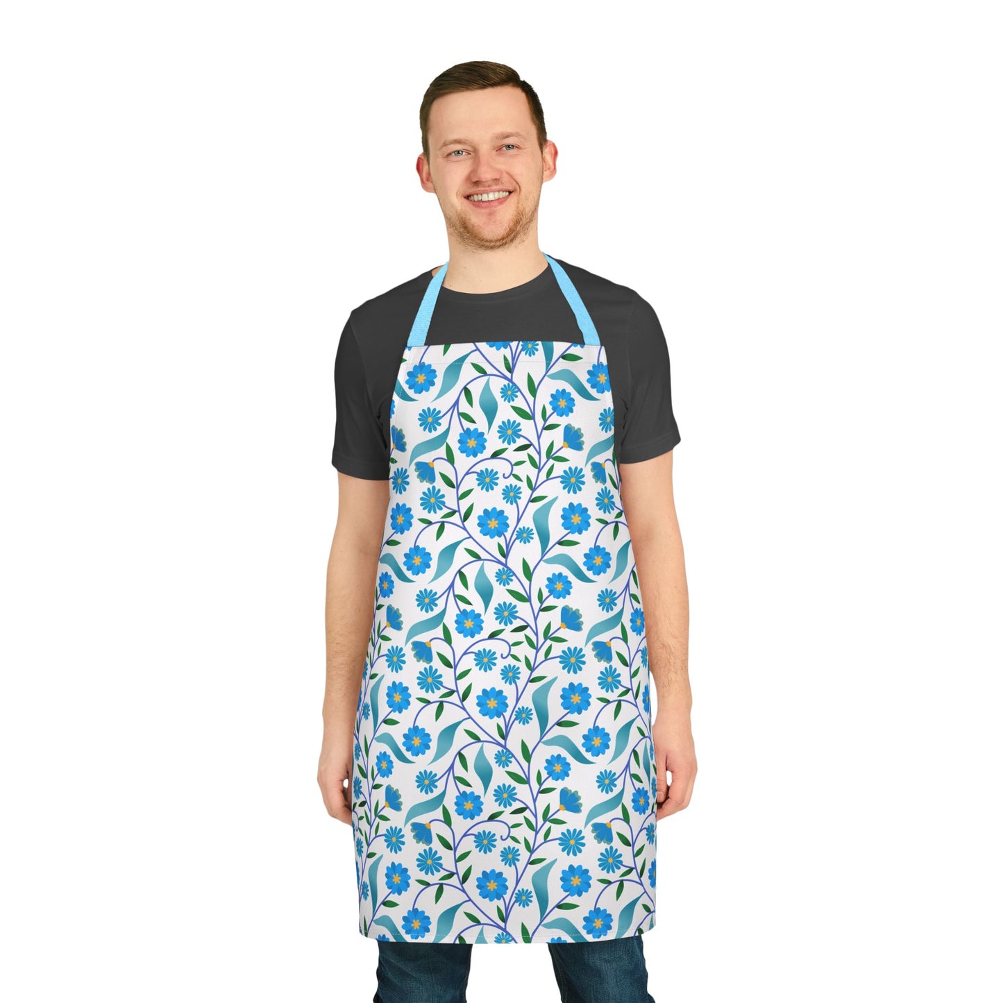 Man wearing Apron Floral Design with blue flowers and green leaves over a dark t-shirt and jeans. This stylish, stain-free apron from FireBrook Designs combines comfort and vibrant patterns, perfect for any kitchen activity.