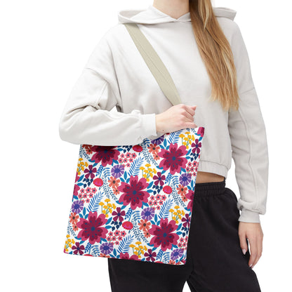 Person holding the Violet Daisy Carnival Tote Bag, featuring a vibrant floral pattern of magenta, pink, and multicolored blooms on a white background, ideal for summer outings.