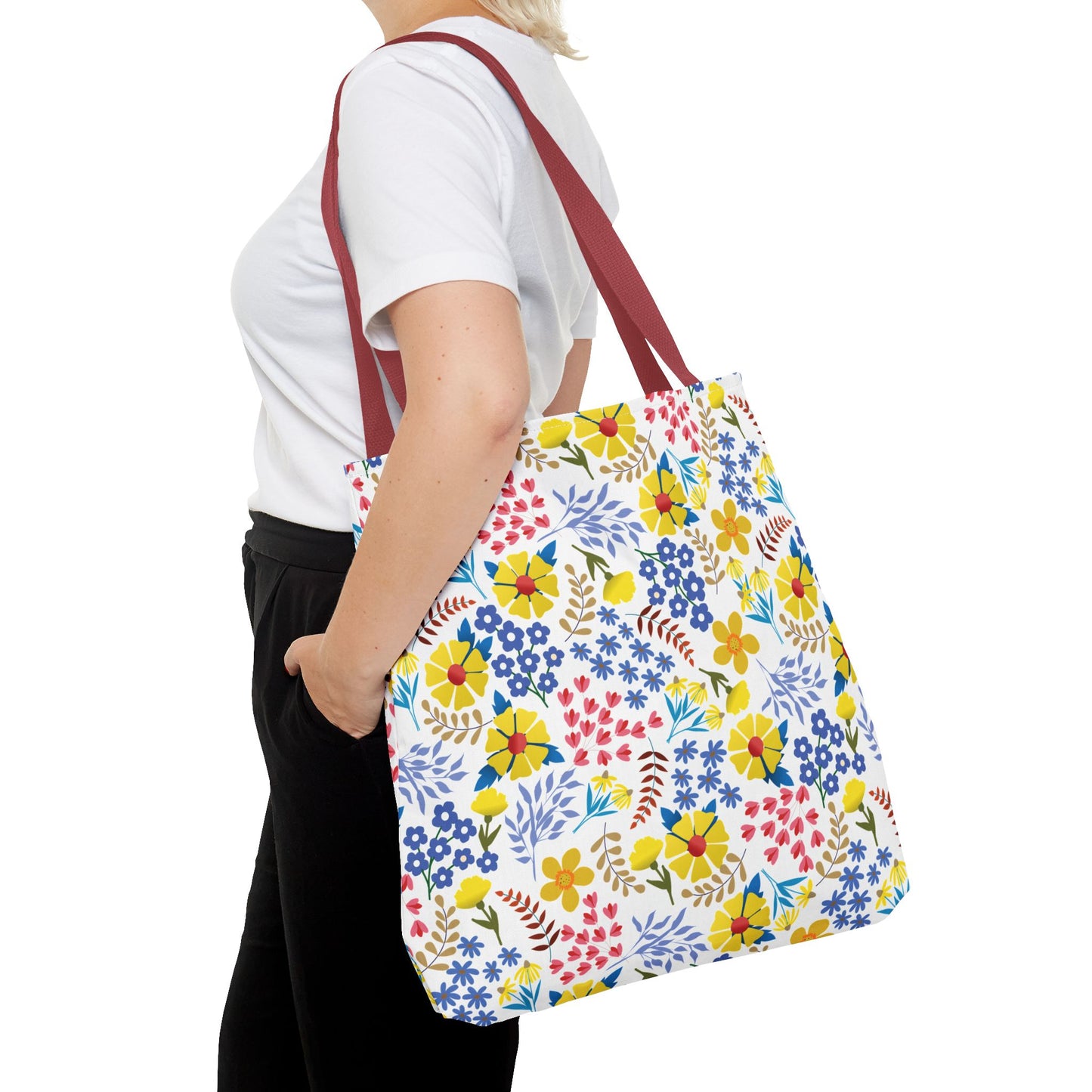 Floral Tote Bag with vibrant floral pattern on white, worn over-the-shoulder by model in white T-shirt and black trousers, ideal for adding a cheerful touch to any outing.