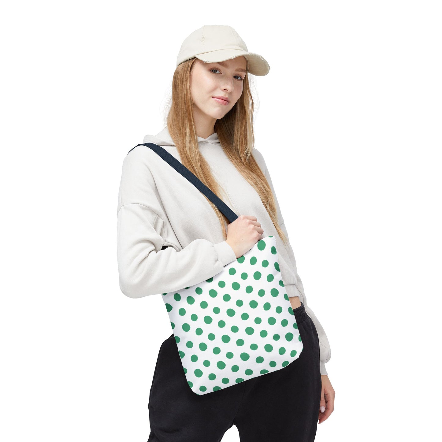 Green Polka Dots Tote Bag, featuring a vibrant design, held by a hand gripping its strap. This playful, durable accessory from FireBrook Essentials adds a cheerful touch to any casual outfit.