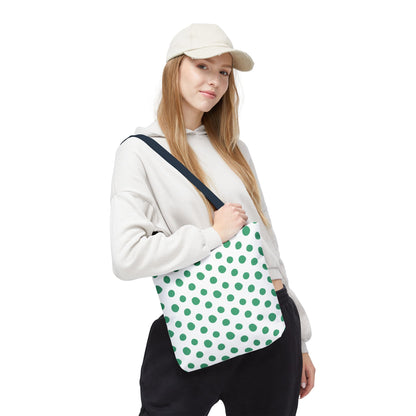 Green Polka Dots Tote Bag, featuring a vibrant design, held by a hand gripping its strap. This playful, durable accessory from FireBrook Essentials adds a cheerful touch to any casual outfit.