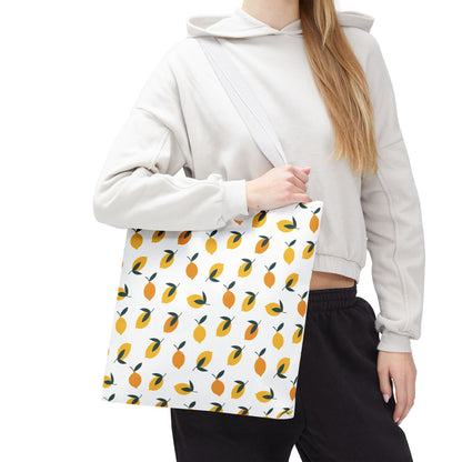 The Lemon Drop Toss Tote Bag, adorned with vibrant lemon motifs, is showcased on a person wearing casual attire. This stylish tote embodies FireBrook Designs' cheerful and uplifting aesthetic, perfect for joyful outings.