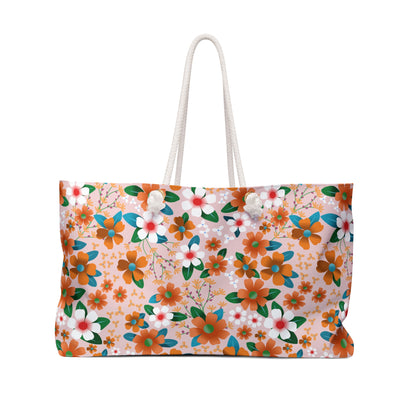 Weekender Bag: A spacious tote-style bag with thick rope handles, featuring an orange floral pattern on a pale pink background, perfect for stylish and joyful travel adventures.