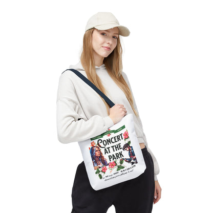 Concert At the Park Tote Bag held by a woman in a white hat and sweatshirt, featuring a lively concert design ideal for outdoor events.