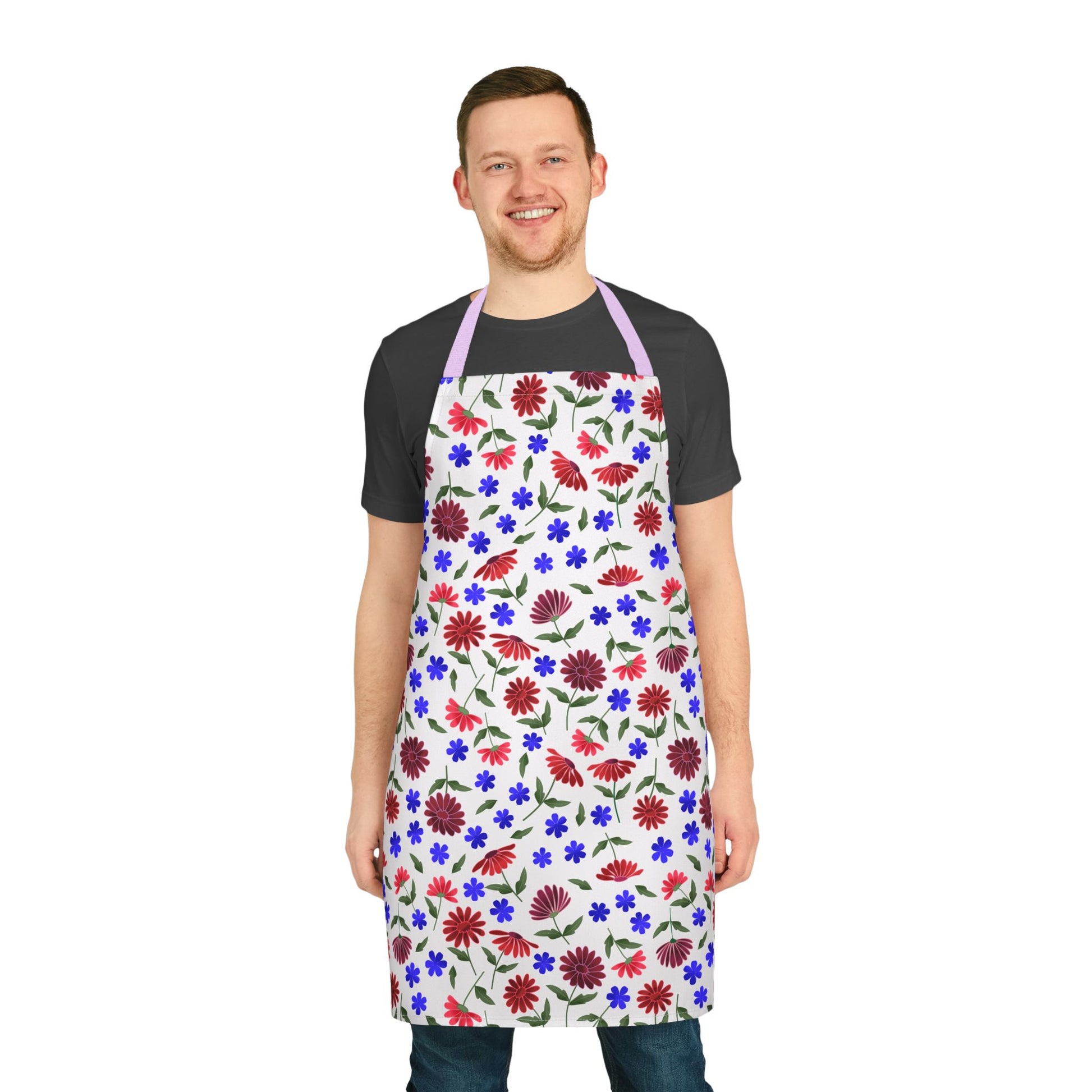 Floral Apron: A smiling man wears a white apron with vibrant red, blue, and purple floral patterns. Ideal for various activities, the apron features a light purple neck strap, emphasizing comfort and style.