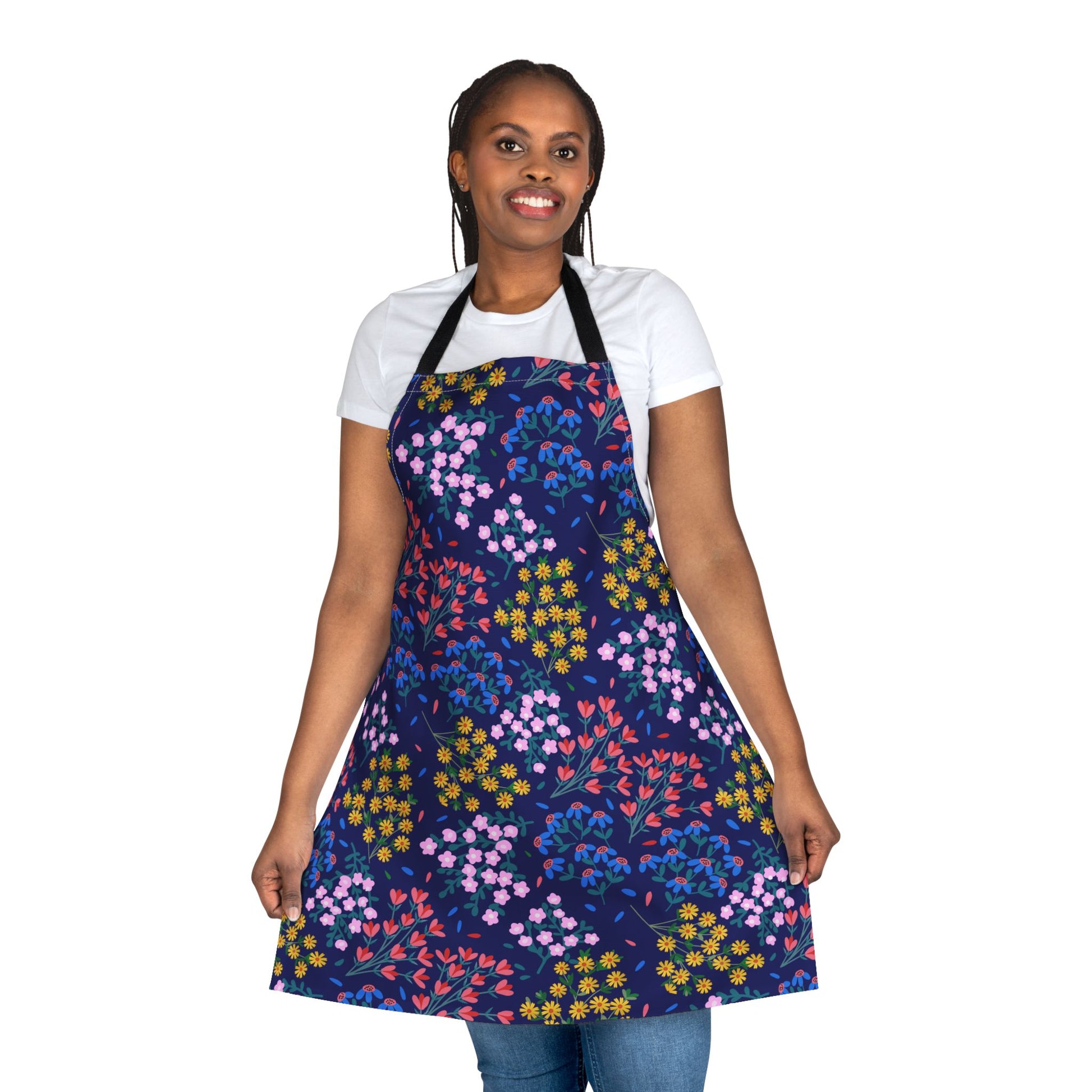 Person wearing the Floral Apron, a navy-blue apron with vibrant small blossoms, over a white T-shirt and blue jeans, showcasing FireBrook Essentials' blend of comfort and uplifting style.