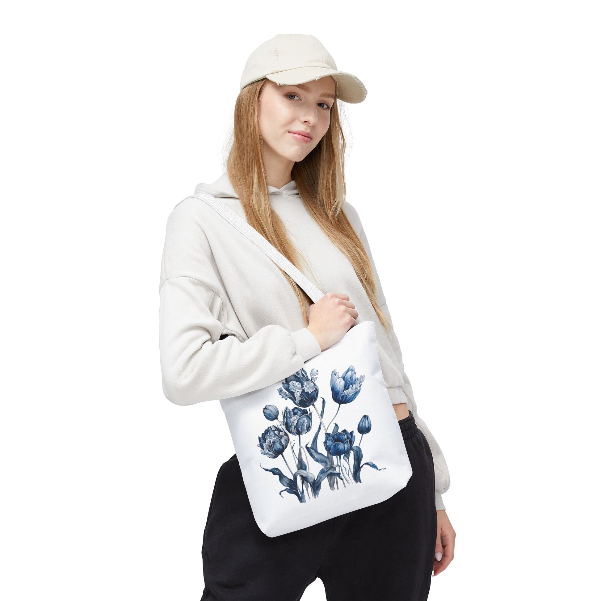 Woman in white sweatshirt holding Flowers in Blue Hue Watercolor Tote Bag, showcasing its floral design and functionality for everyday use.