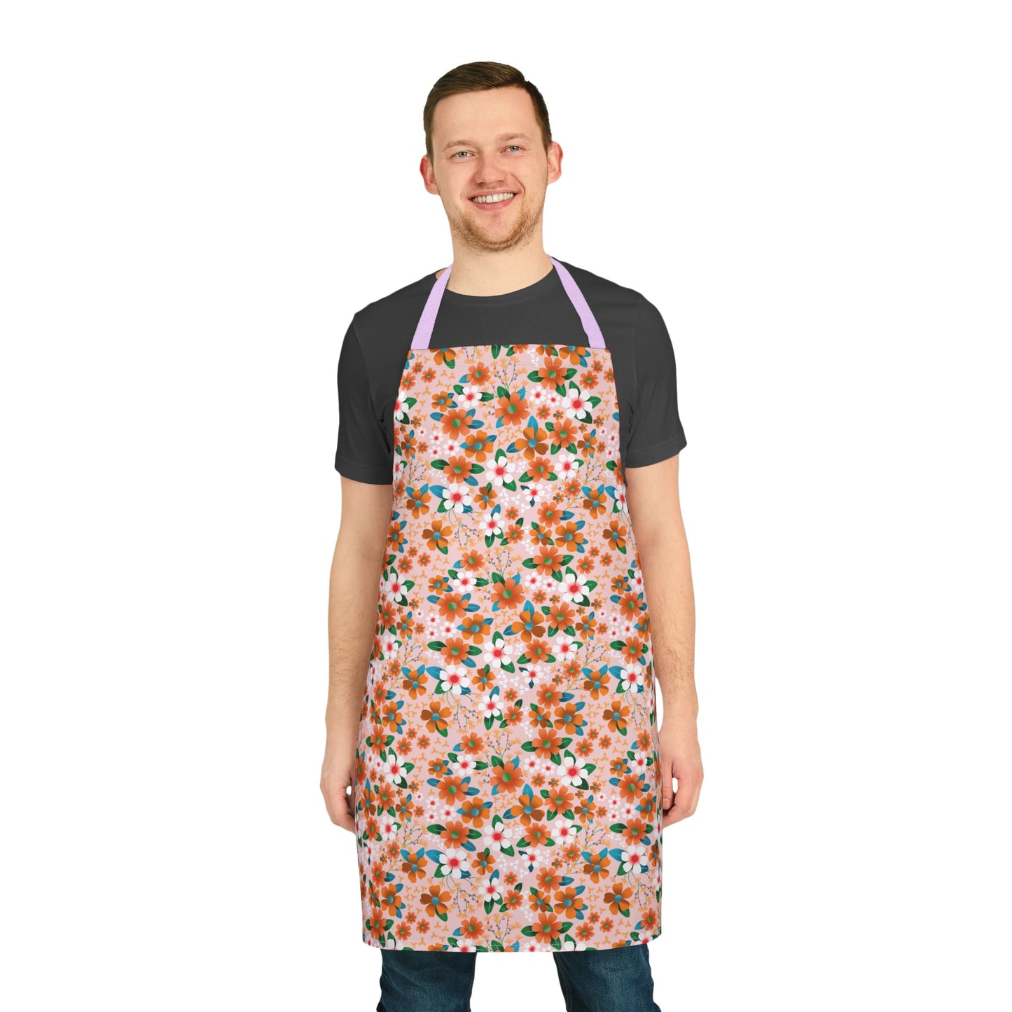 Young man models the Floral Apron from FireBrook Designs, featuring a pastel pink floral pattern. This stain-free, 100% polyester canvas apron combines style and comfort, suitable for cooking, baking, or crafting.