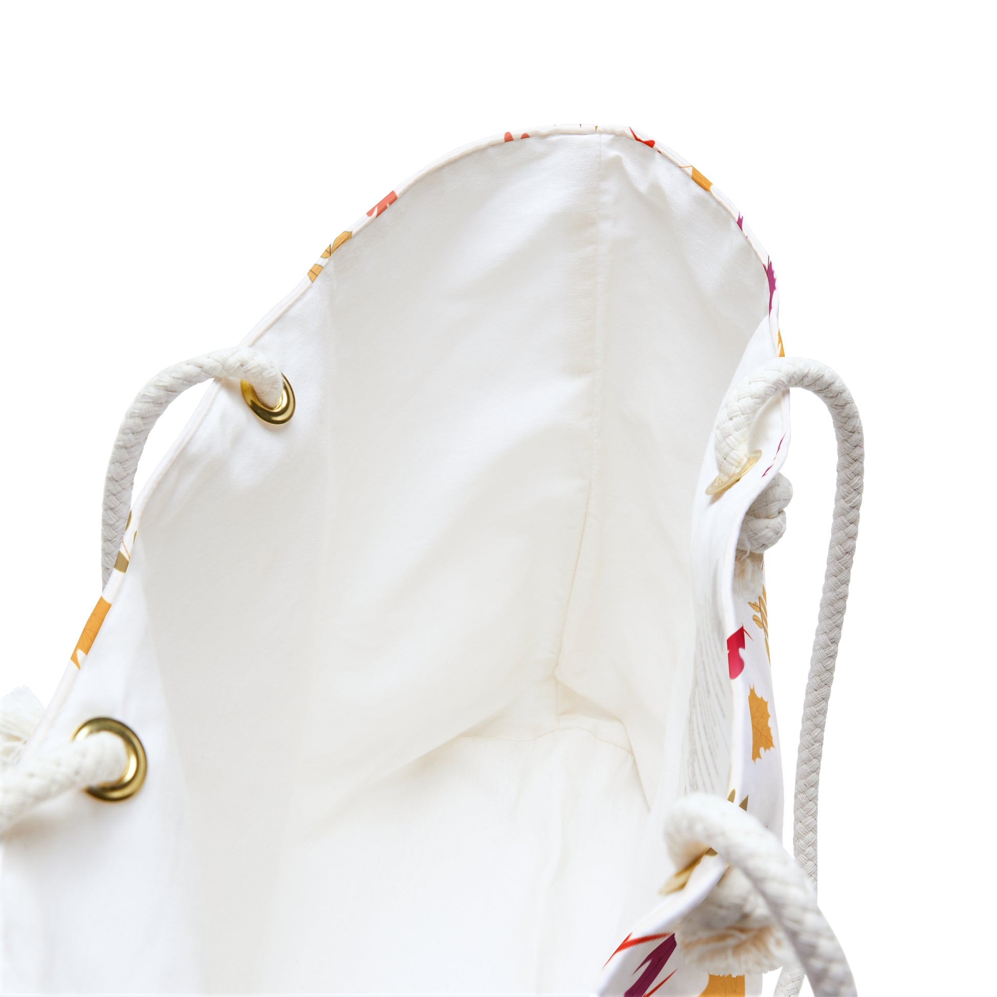 Weekender Bag with cream lining viewed from above, showcasing thick rope handles through brass grommets and hints of a colorful leaf-print pattern on the outer sides, ideal for stylish travel.