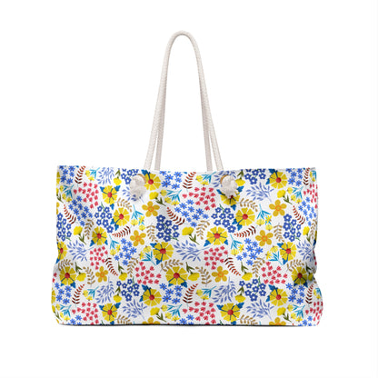 Weekender Bag with colorful floral print on white canvas, featuring thick rope handles. Ideal for stylish weekend getaways, this bag from FireBrook Essentials adds a vibrant touch to your travels.