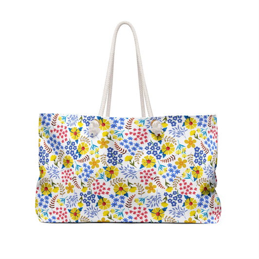 Weekender Bag with colorful floral print on white canvas, featuring thick rope handles. Ideal for stylish weekend getaways, this bag from FireBrook Essentials adds a vibrant touch to your travels.