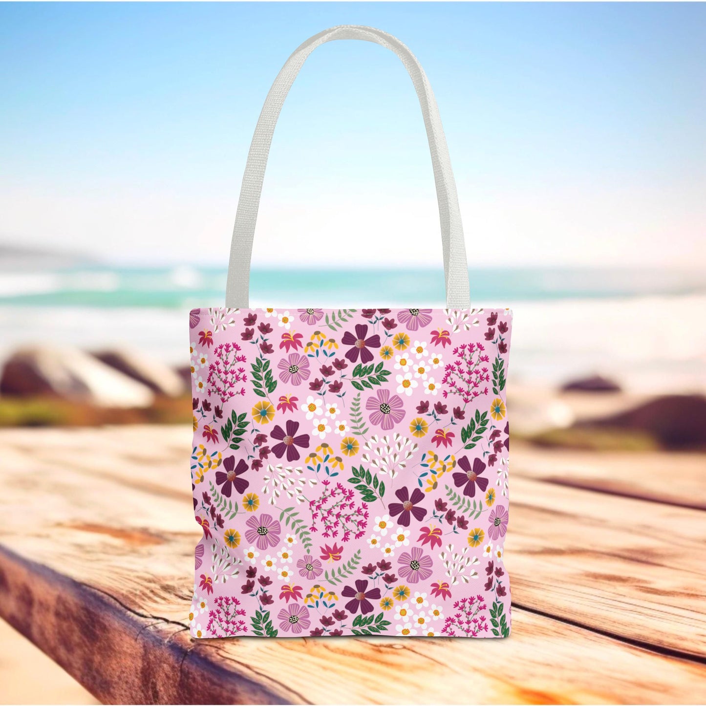 Floral Tote Bag on a wooden surface, featuring a ditsy floral pattern with white straps. Ideal for daily use, it exemplifies FireBrook Essentials' commitment to stylish, durable, and positive lifestyle accessories.
