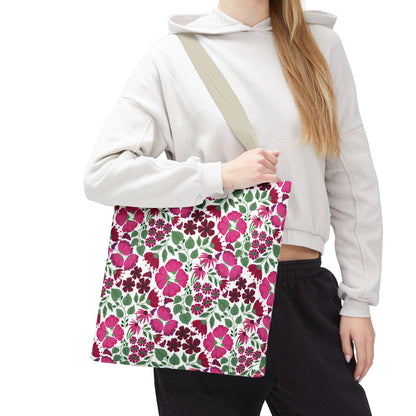 Pink Lady Tote Bag features a vibrant pink, burgundy, and green floral pattern on white, carried by a person in a light hoodie. Ideal for adding color and joy to everyday outfits.