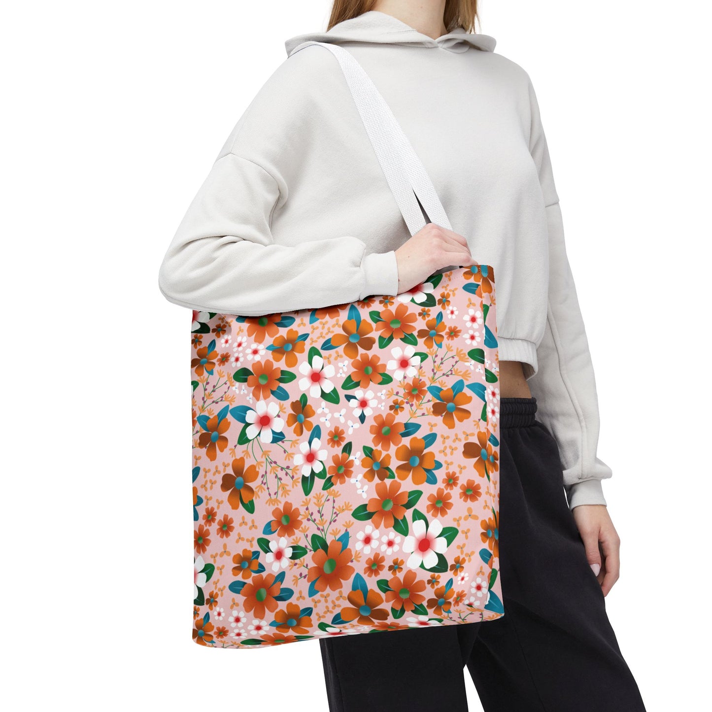 Peach Poppy Grove Tote Bag: A large tote with vibrant orange and white floral patterns against pale pink, worn over the shoulder, perfect for summer outings, offering durability and cheerful design.