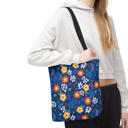 Person wearing a light hoodie and dark pants carries the Cornflower Patch Tote Bag, featuring a bright blue background with vibrant floral patterns, ideal for cheerful, summer outings.