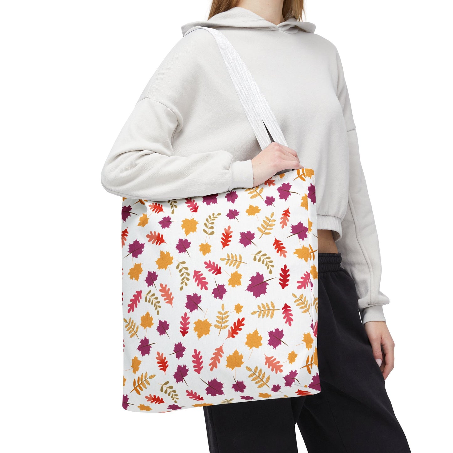 Autumn Leaves Tote Bag draped over a shoulder, showcasing an all-over autumn-leaf motif. Ideal for everyday use with reinforced stitching and boxed corners, embodying FireBrook Essentials' blend of style and practicality.
