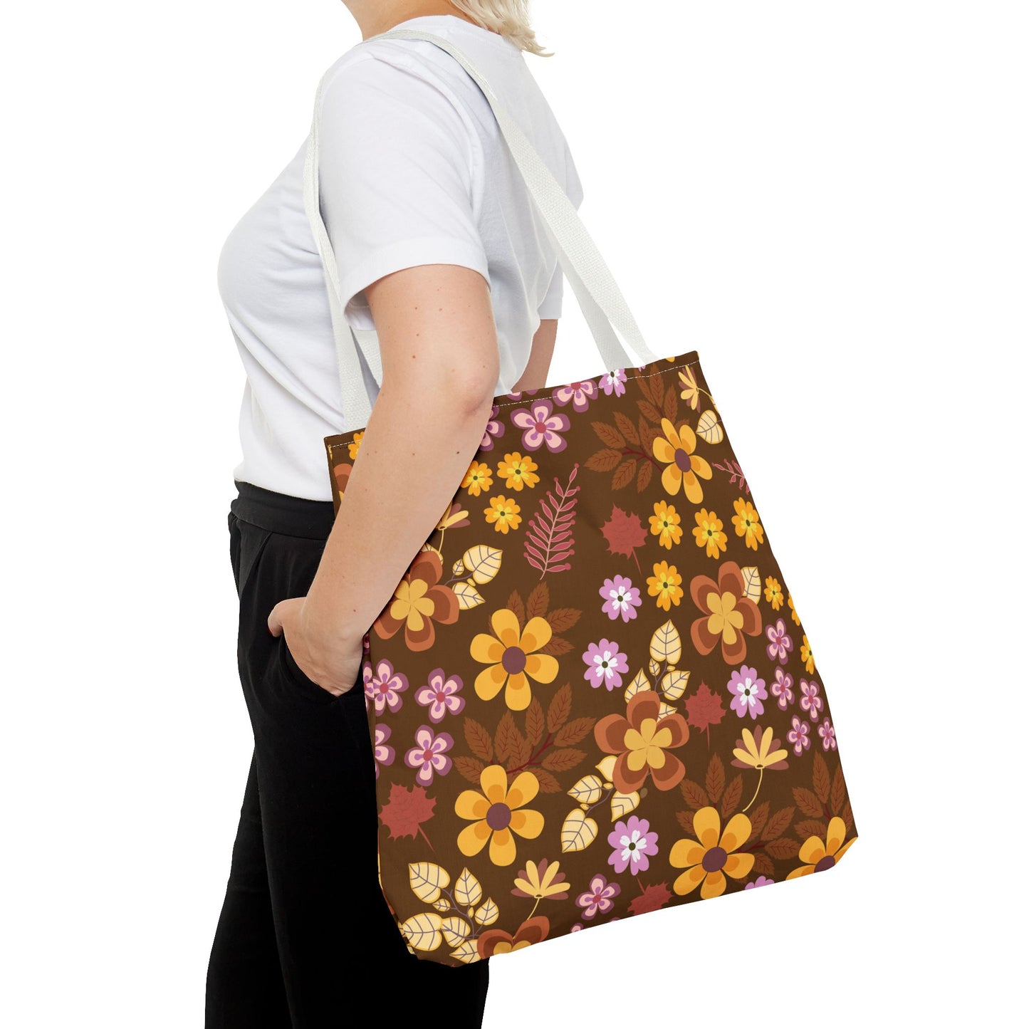 Person wearing a plain white T-shirt carries the Floral Tote Bag with vibrant orange, yellow, pink, and purple flowers, showcasing FireBrook Designs' blend of style and functionality for joyful outings.