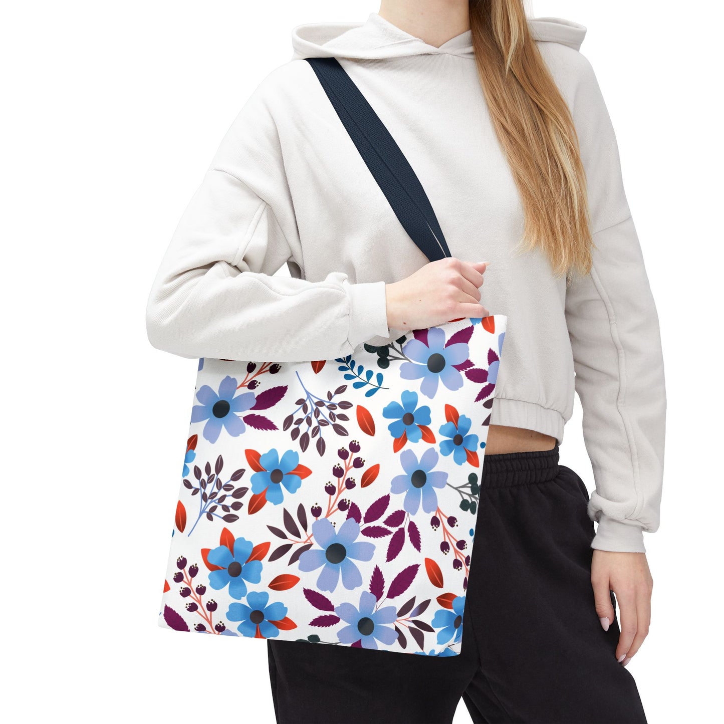 Floral Tote Bag with vibrant blue, red, and purple blossoms, carried by a person wearing a light hoodie. Features dark shoulder strap for comfort, perfect for summer outings by FireBrook Designs.