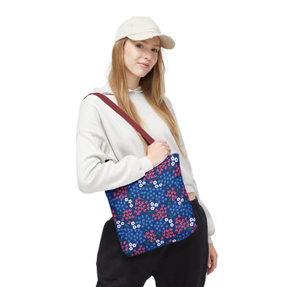 Berry Blue Festival Tote Bag with dark blue floral pattern, burgundy strap, worn over shoulder by model in off-white hoodie and black pants; perfect for vibrant, casual outings.