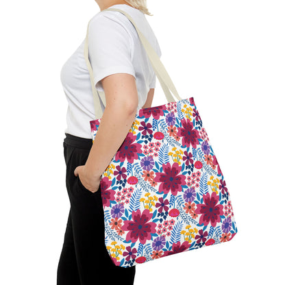 Floral Tote Bag with colorful blooms and blue-green leaves, carried by a person in a white T-shirt, epitomizes FireBrook Designs' vibrant and joyful aesthetic. Perfect for summer outings.