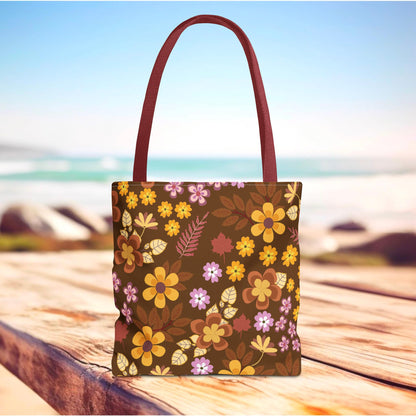 Floral Tote Bag on a wooden surface with a vibrant floral pattern, featuring orange and mustard blossoms. Ideal for summer outings, this durable, stylish bag embodies FireBrook Essentials' cheerful and uplifting design ethos.