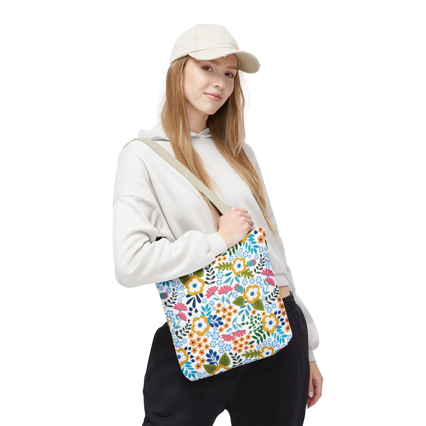 Young woman wearing a light hoodie and black pants models the Floral Tote Bag, showcasing its cheerful floral pattern and sturdy design, perfect for summer outings and casual style.