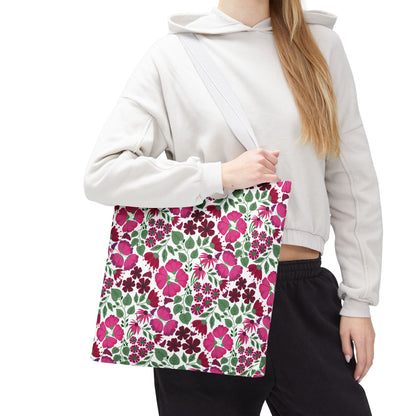 A person holds the Pink Lady Tote Bag featuring vibrant pink and burgundy floral patterns. This cheerful, durable tote complements their casual attire, embodying FireBrook Designs' uplifting and stylish ethos.