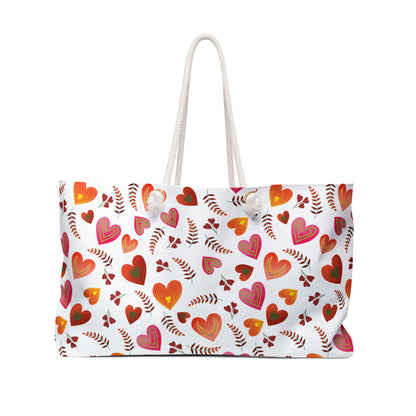 Weekender Bag with rope handles, featuring a playful pattern of hearts and leaves on white fabric, perfect for stylish travel. Ideal for getaways, offering ample space and a luxurious interior.