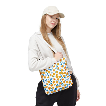 Young woman in casual attire carries the Buttercup Cream Tote Bag, featuring a cheerful yellow-orange floral pattern on white canvas, ideal for summer outings and reflecting FireBrook Designs' uplifting style.