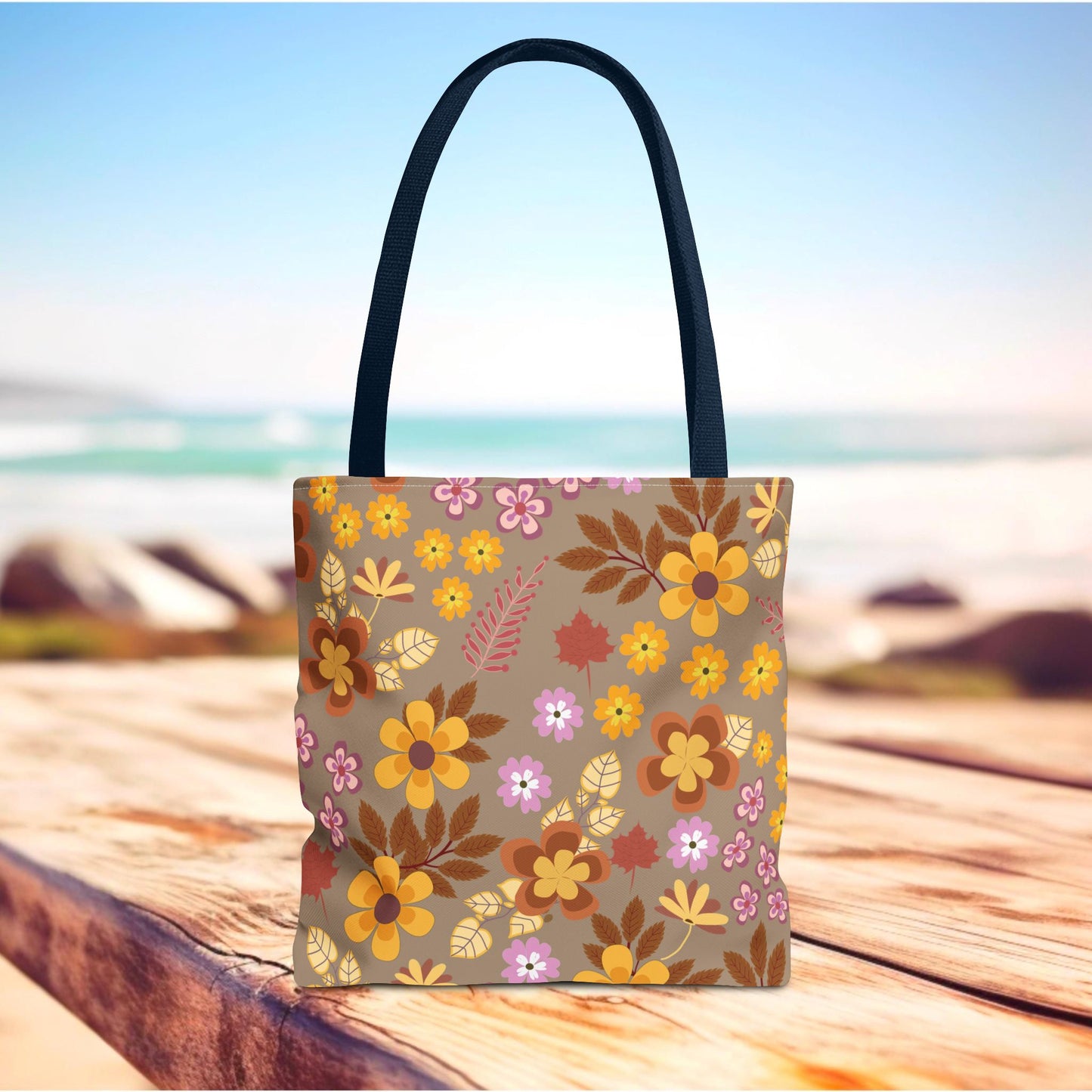 Harvest Brown Bloom Tote Bag on a weathered wooden surface, featuring vibrant floral patterns with black handles. Ideal for summer outings, embodying FireBrook Designs' uplifting and joyful style.