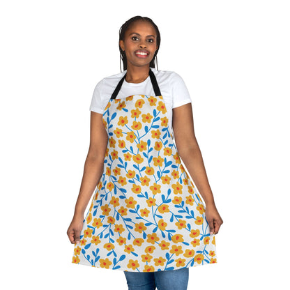 Person wearing a Floral Apron with vibrant yellow flowers, red centers, and blue stems. The apron features black neck straps and a tie-back closure, ideal for comfort and style.