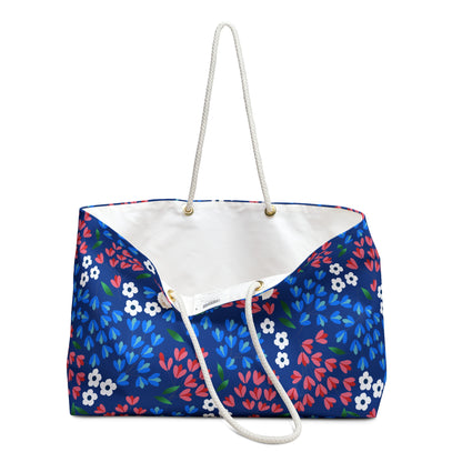 The Weekender Bag features a deep blue floral print and sturdy white rope handles, ideal for stylish travel. Its spacious interior and luxurious lining make it perfect for joyful getaways.