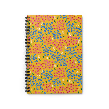 Floral Spiral Notebook featuring a mustard-yellow cover with a vibrant, repeating floral pattern of pink and blue teardrop petals, green leaves, and white dots, ideal for creative journaling and note-taking.