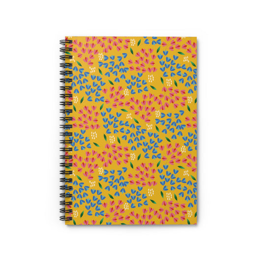 Floral Spiral Notebook featuring a mustard-yellow cover with a vibrant, repeating floral pattern of pink and blue teardrop petals, green leaves, and white dots, ideal for creative journaling and note-taking.