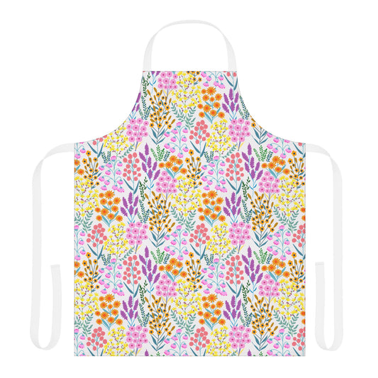 Floral Apron features a vibrant wildflower pattern in pink, orange, yellow, purple, and teal on a white polyester canvas. It includes a white neck loop and waist ties for a cheerful, stylish look.