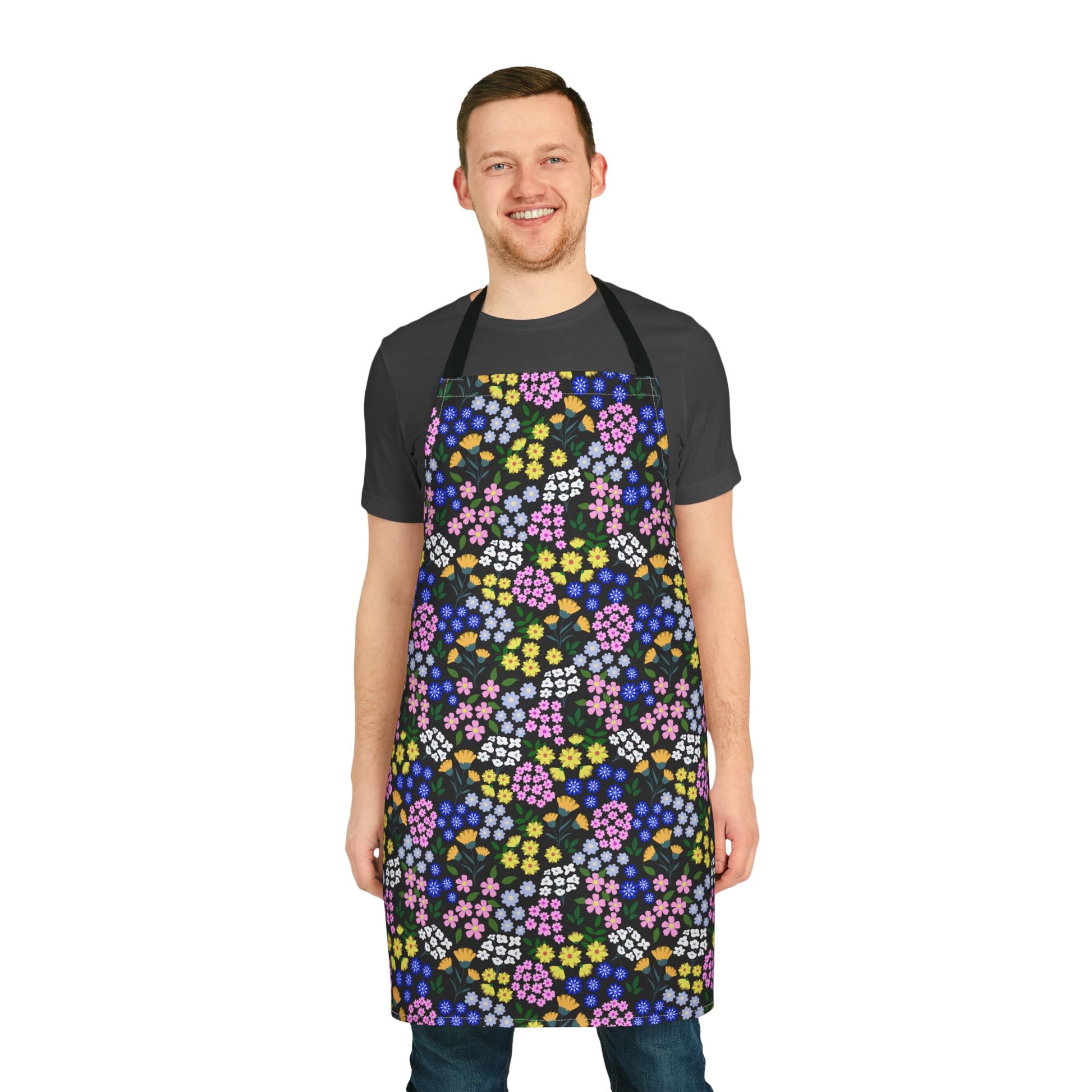 Young man models the Apron Floral Design, showcasing its vibrant, multicolored floral print on a black background, emphasizing comfort with its polyester canvas and foam lining for joyful cooking experiences.